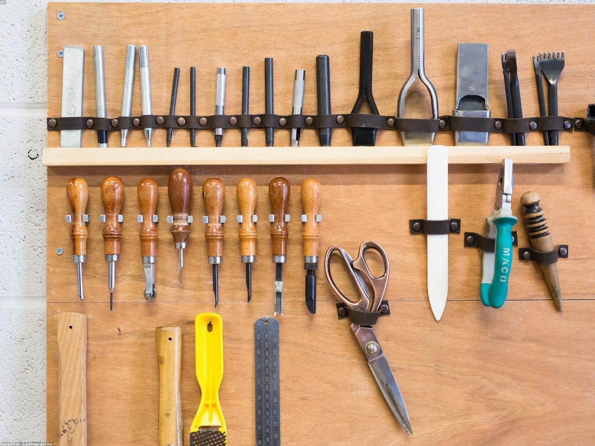 Bottega artigiana toscana: pelli conciate, strumenti in legno, luce naturale attraverso alte finestre